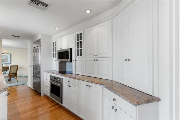 a large white kitchen with stainless steel appliances granite countertop a stove and a refrigerator