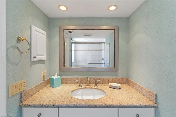 a bathroom with a granite countertop sink and a mirror