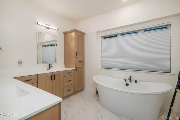 a bathroom with a tub sink and mirror