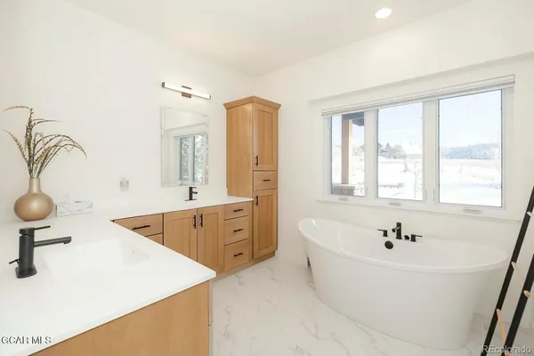 a spacious bathroom with sink a mirror a bathtub and window