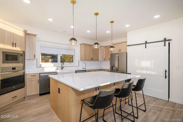 a kitchen with stainless steel appliances granite countertop table chairs sink refrigerator and cabinets