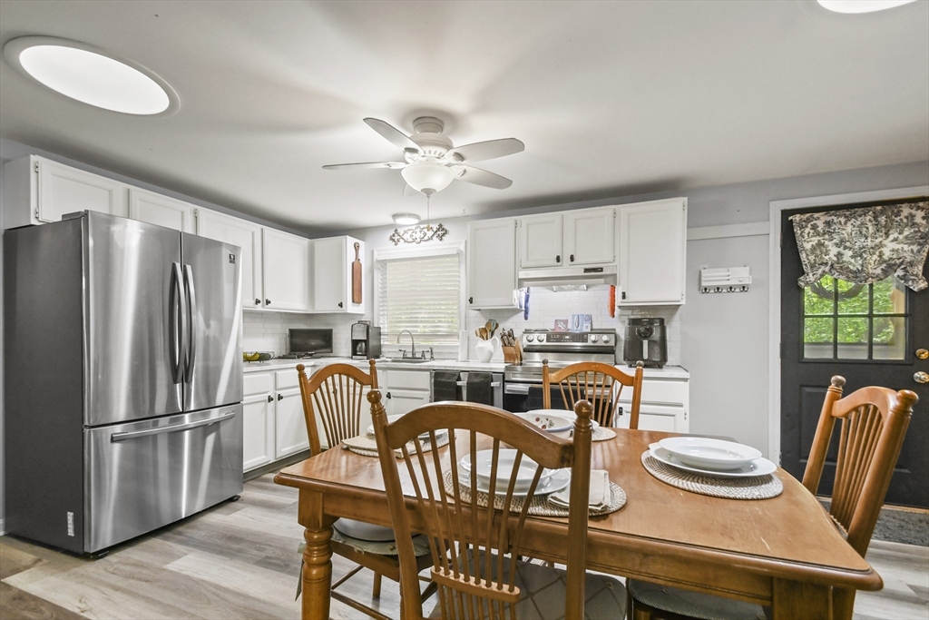 231 Georgetown Road Boxford, MA 01921 - Photo 8 of 28 a kitchen with stainless steel appliances granite countertop a dining table chairs and a refrigerator