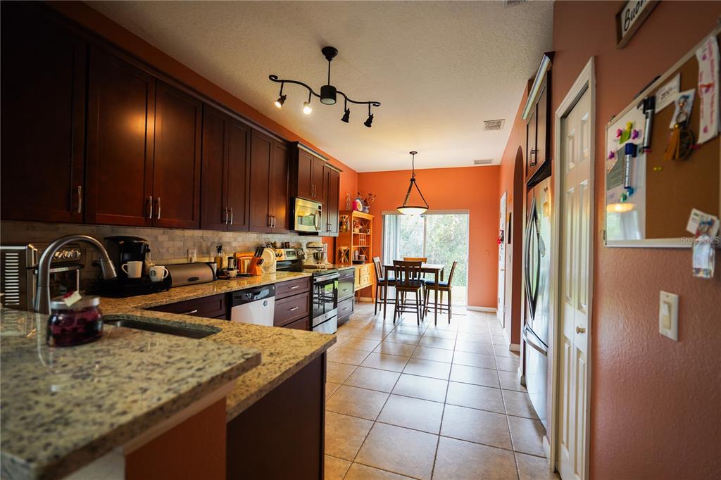 16307 Old Ash Loop Orlando, FL 32828 - Photo 5 of 26 a kitchen with stainless steel appliances granite countertop a sink a stove and a refrigerator with wooden floor