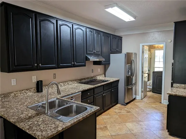 a kitchen with granite countertop a sink stove and refrigerator