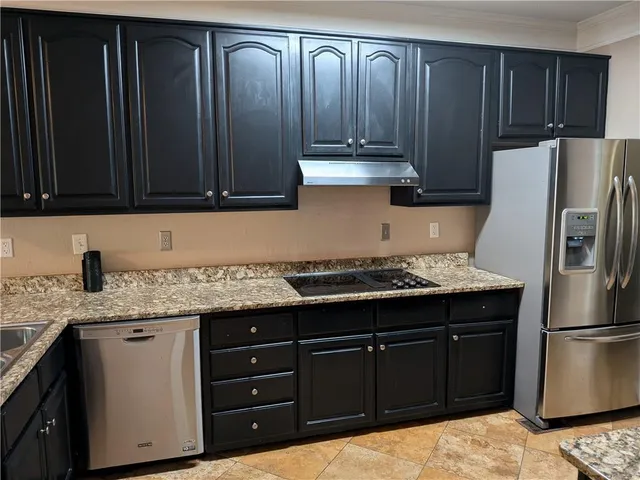 a kitchen with granite countertop wooden cabinets and refrigerator