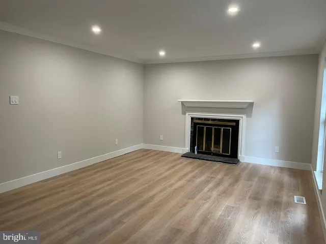 a view of empty room with wooden floor and fireplace