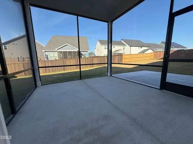 a view of an empty room with wooden floor and windows