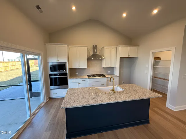 a kitchen with kitchen island granite countertop wooden cabinets a sink and a stove
