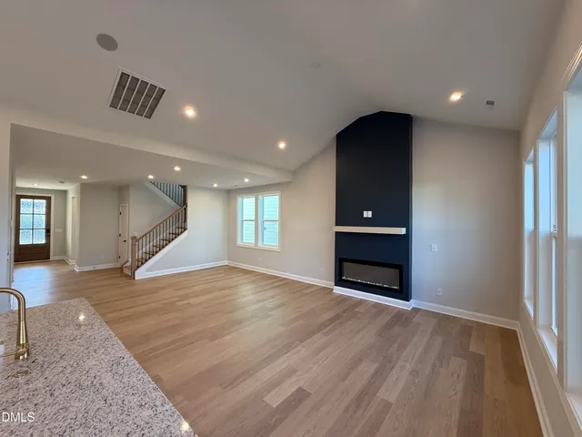 an empty room with wooden floor wooden cabinet and windows