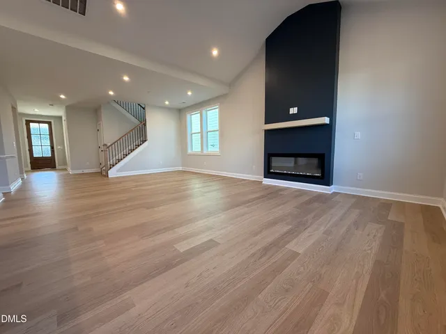an empty room with wooden floor fireplace and windows