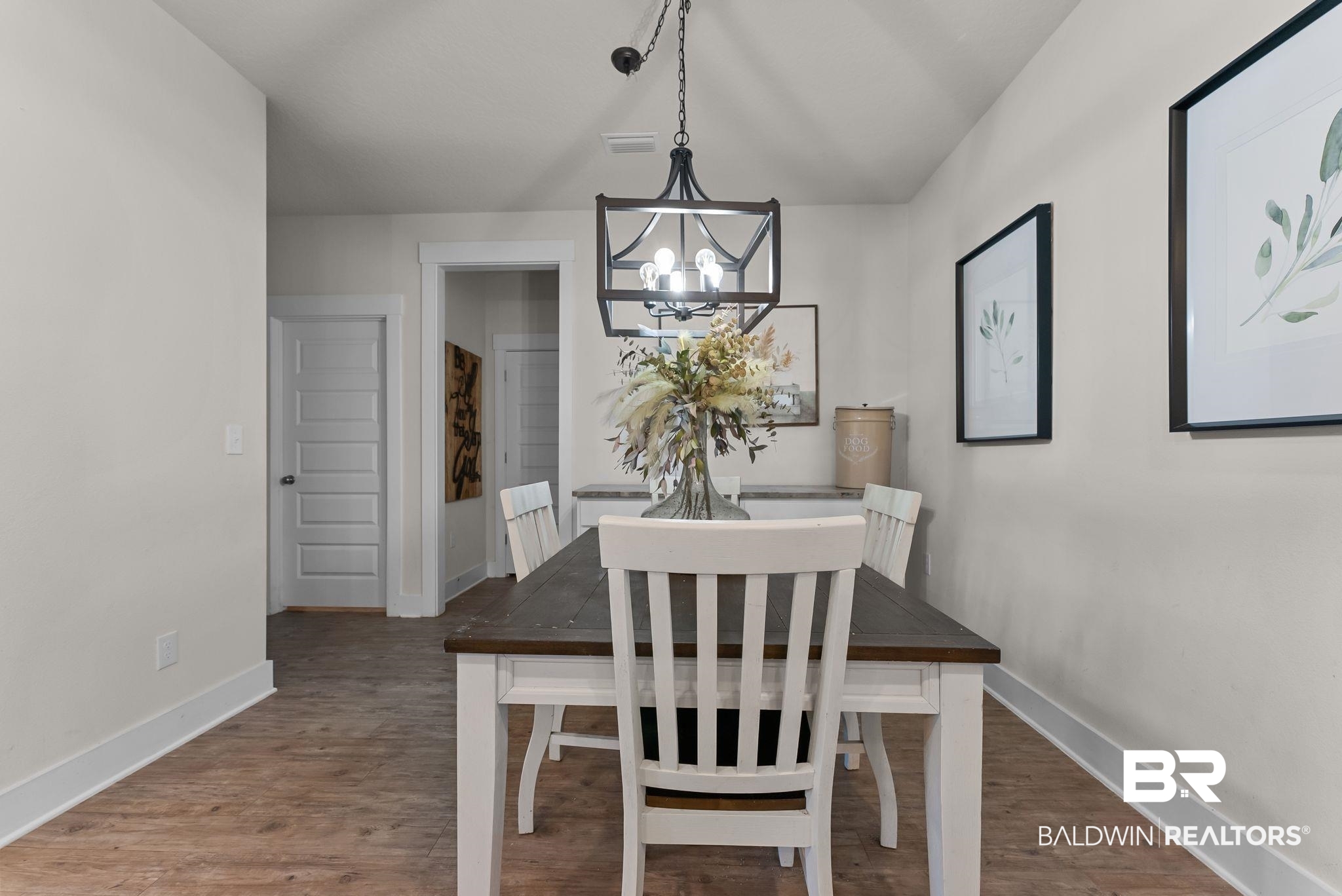 16607 Prado Loop Loxley, AL 36551 - Photo 10 of 46 Dining area featuring wood-finish flooring, a dark-stained wood-top table with white base, white walls, and a black metal chandelier