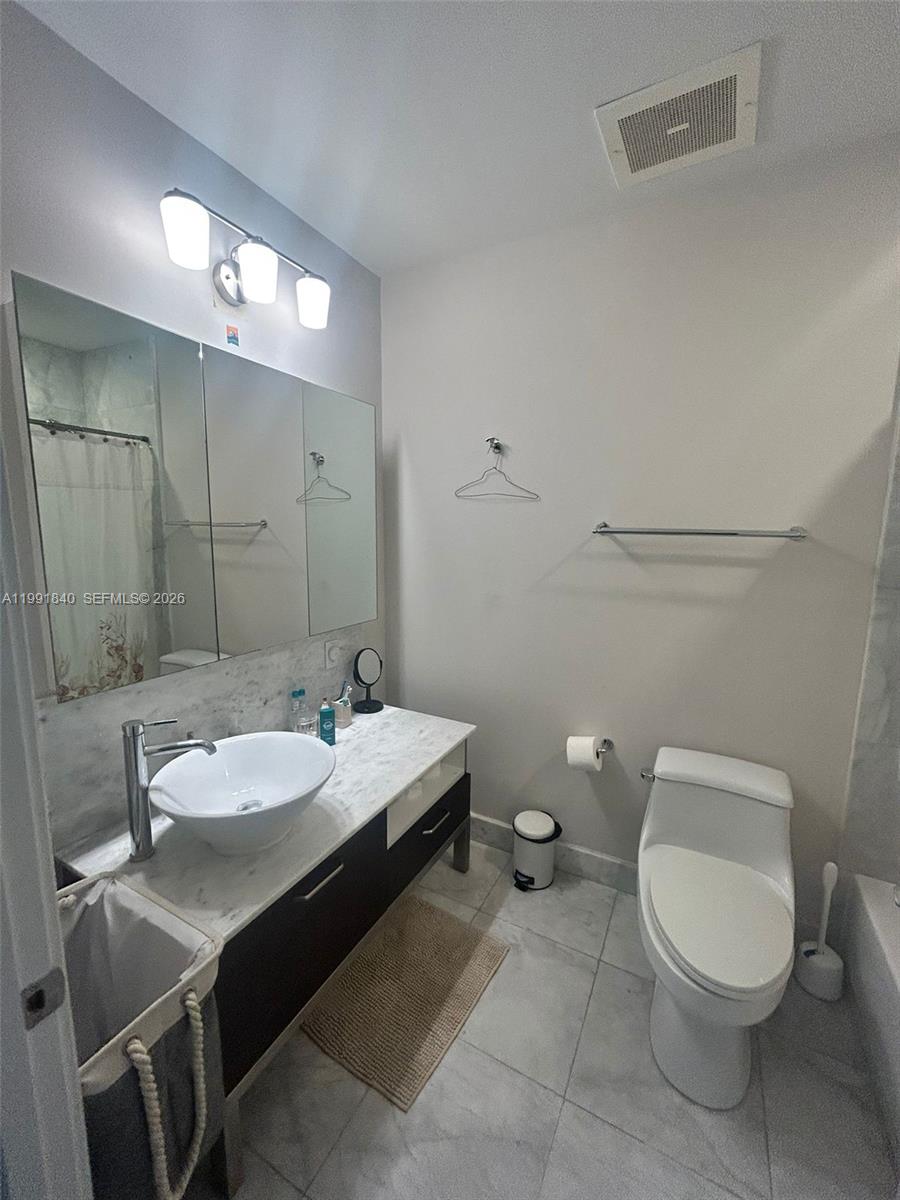 218 Southeast 14th Street, Unit TS303 Miami, FL 33131 - Photo 11 of 16 a bathroom with a toilet a sink and mirror