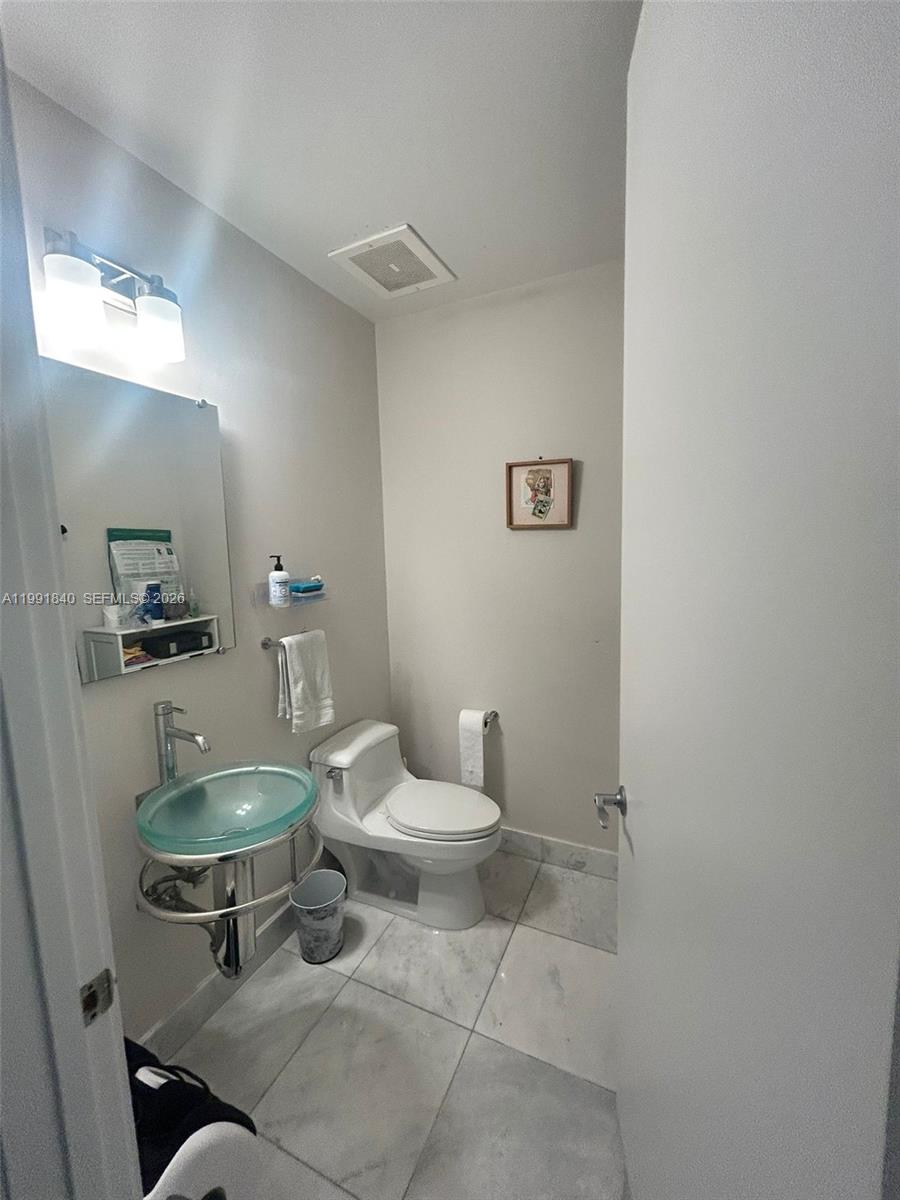 218 Southeast 14th Street, Unit TS303 Miami, FL 33131 - Photo 10 of 16 a bathroom with a toilet a sink and mirror