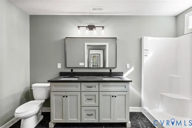 a bathroom with a granite countertop toilet a sink and a mirror