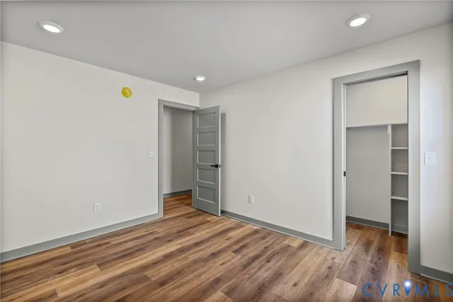 a view of an empty room with wooden floor and closet