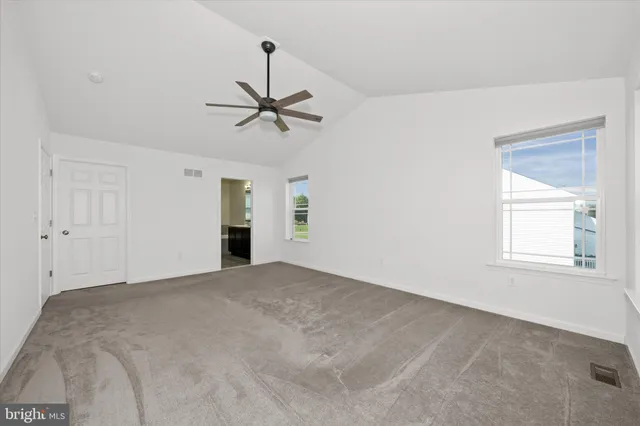 an empty room with windows and fan