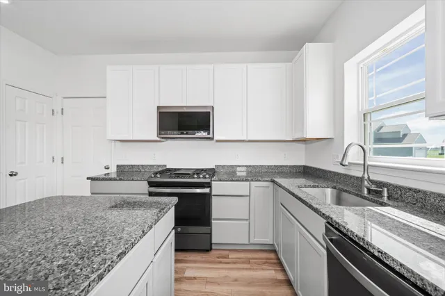 a kitchen with granite countertop a stove a sink and a refrigerator