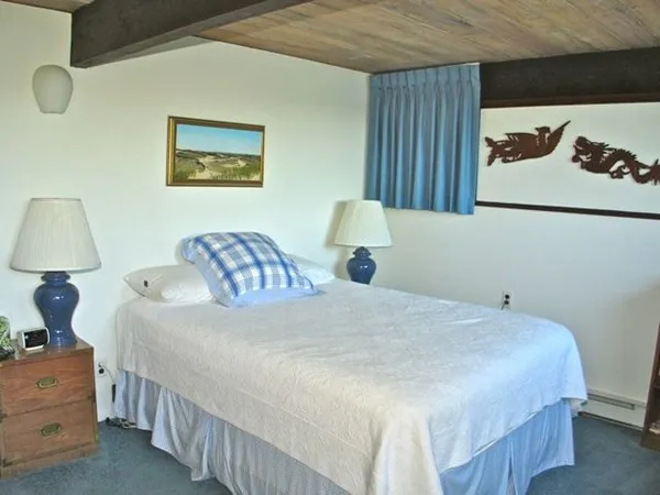 a bedroom with a bed and a lamp on dresser