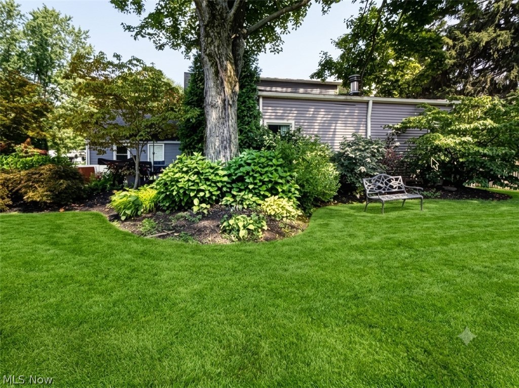 7990 Stockbridge Road Mentor, OH 44060 - Photo 35 of 36 Expansive lawn with mature trees and established landscaping, featuring a decorative metal bench