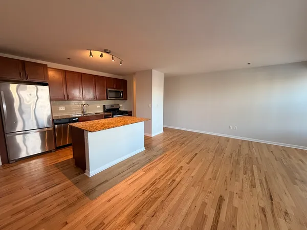 a kitchen with wooden floors a refrigerator and wooden cabinets