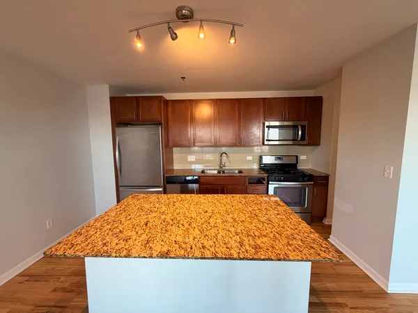 a large kitchen with a large counter top stainless steel appliances and cabinets