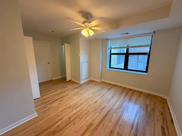 a view of an empty room with wooden floor and a window