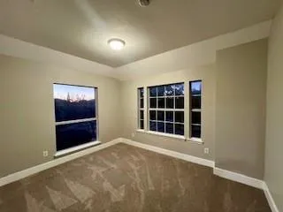 a view of an empty room with a window and kitchen with sink