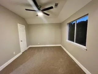 an empty room with a ceiling fan and window