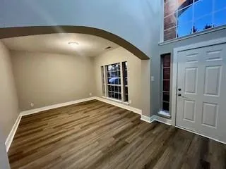 a view of an empty room with wooden floor and windows