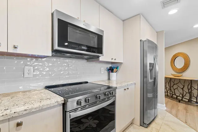 a kitchen with stainless steel appliances granite countertop a dining table chairs refrigerator and sink