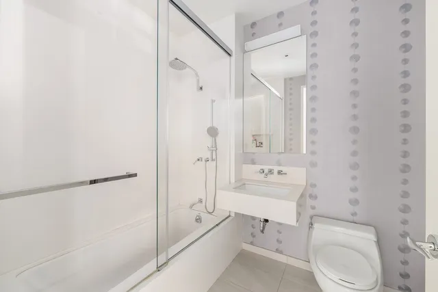 a bathroom with a toilet a sink a mirror and shower