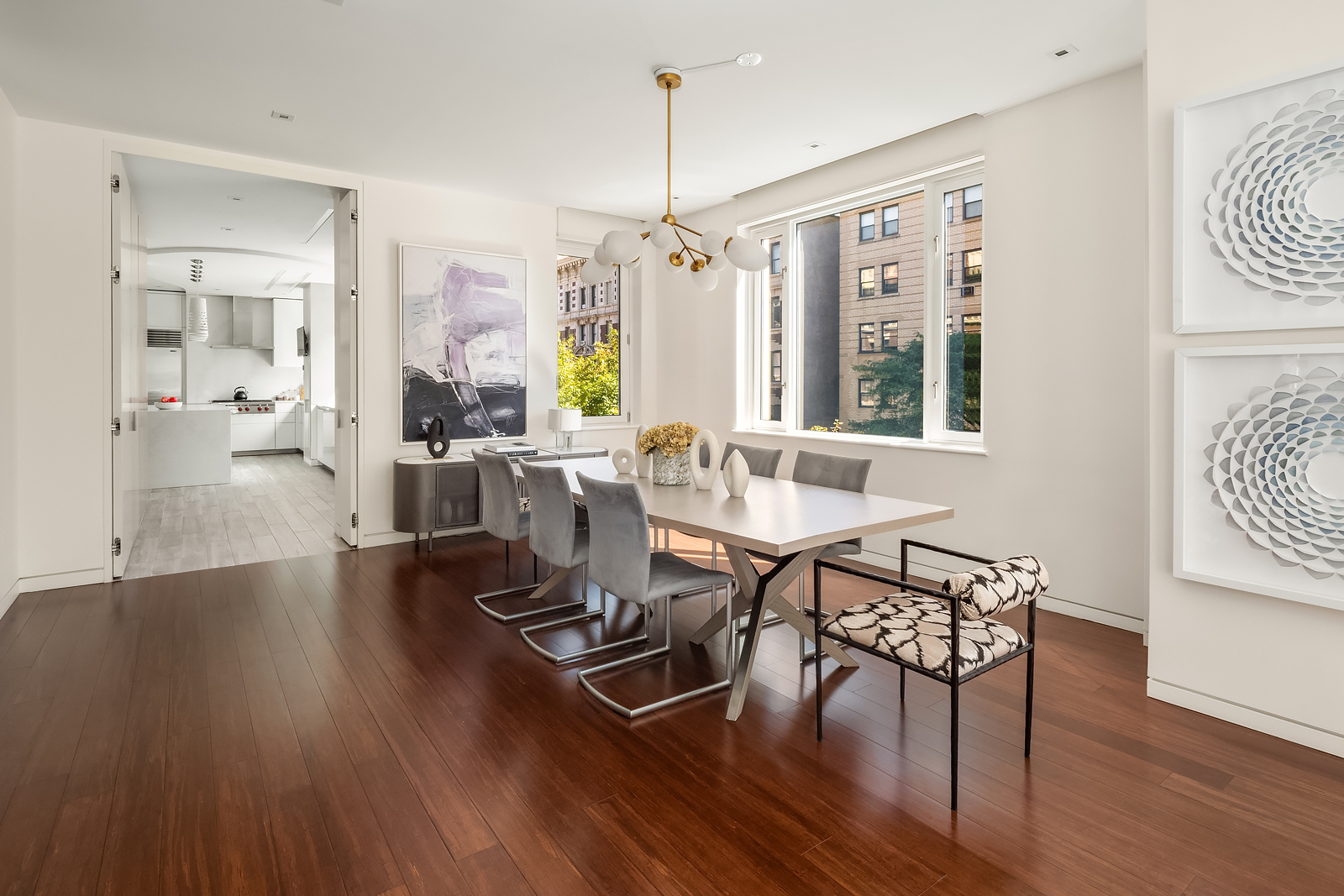 21 East 96th Street, Unit 3/4 Manhattan, NY 10128 - Photo 5 of 25 a dining room with wooden floor a chandelier a glass table and chairs