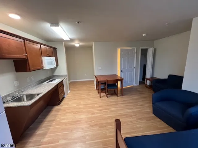 a living room with stainless steel appliances kitchen island granite countertop furniture a rug and a large window
