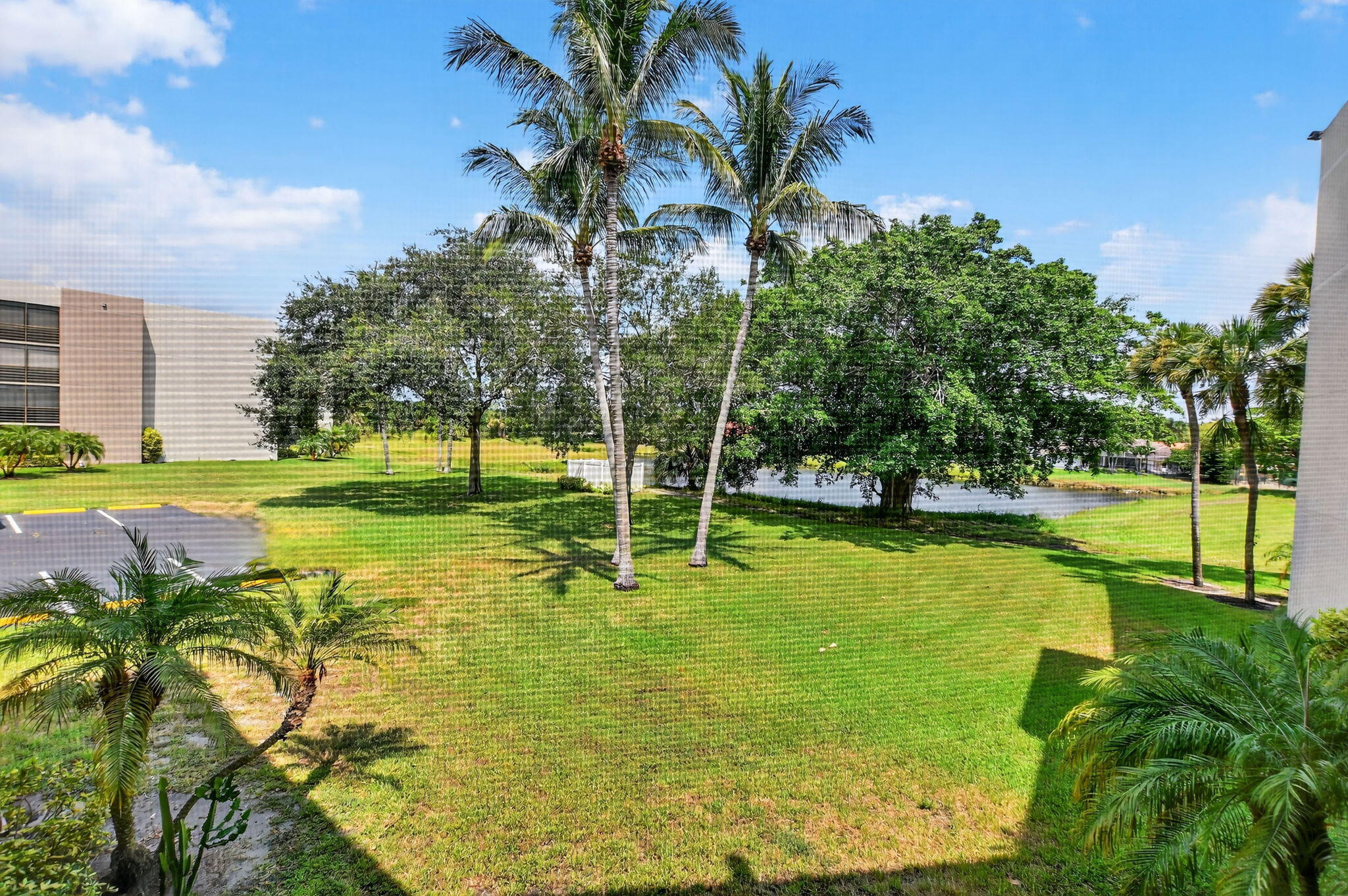 5650 Camino Del Sol, Unit 200 Boca Raton, FL 33433 - Photo 2 of 38 a view of a swimming pool with a garden and trees