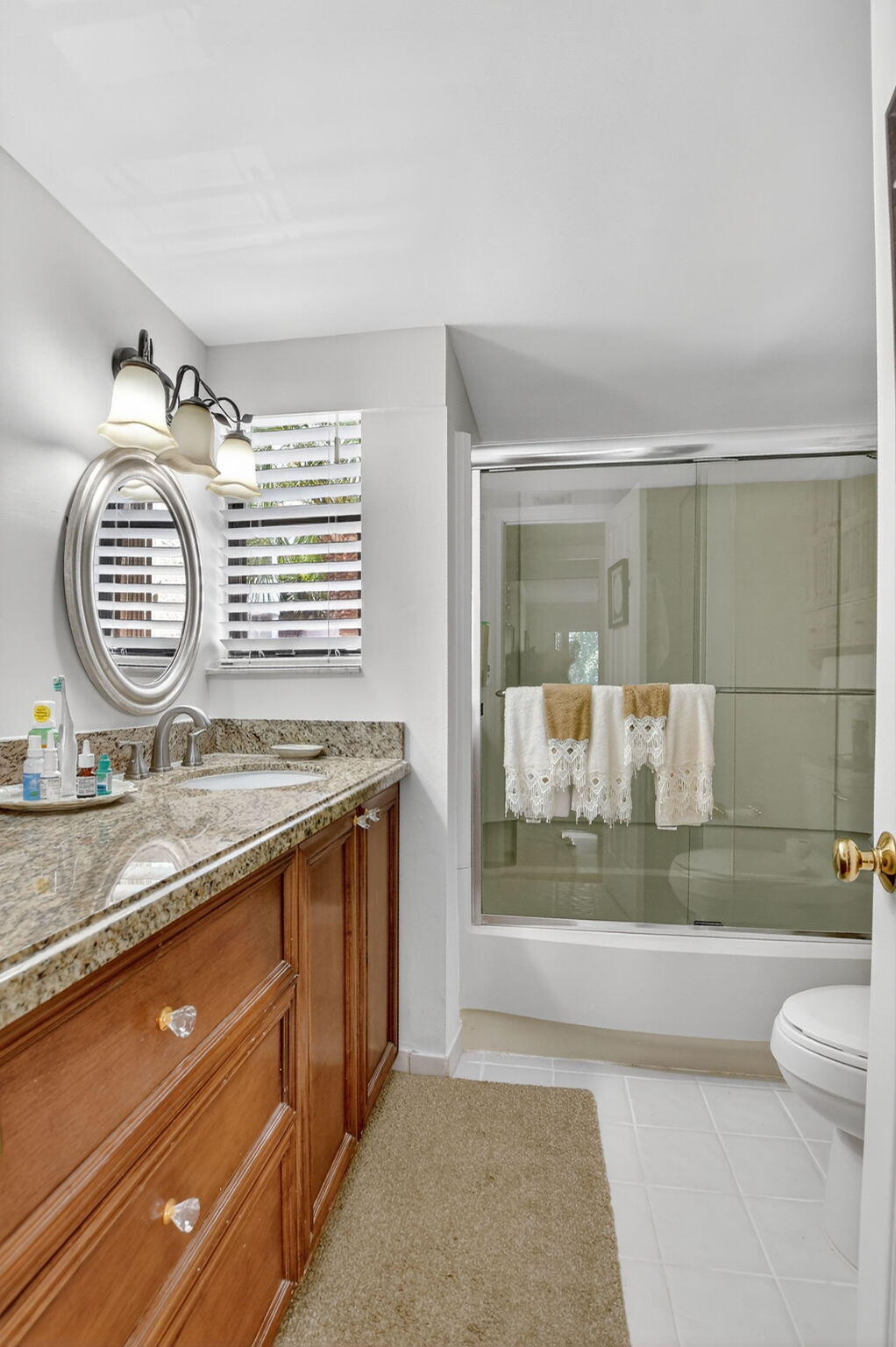 5650 Camino Del Sol, Unit 200 Boca Raton, FL 33433 - Photo 25 of 38 a bathroom with a granite countertop sink a mirror and a shower