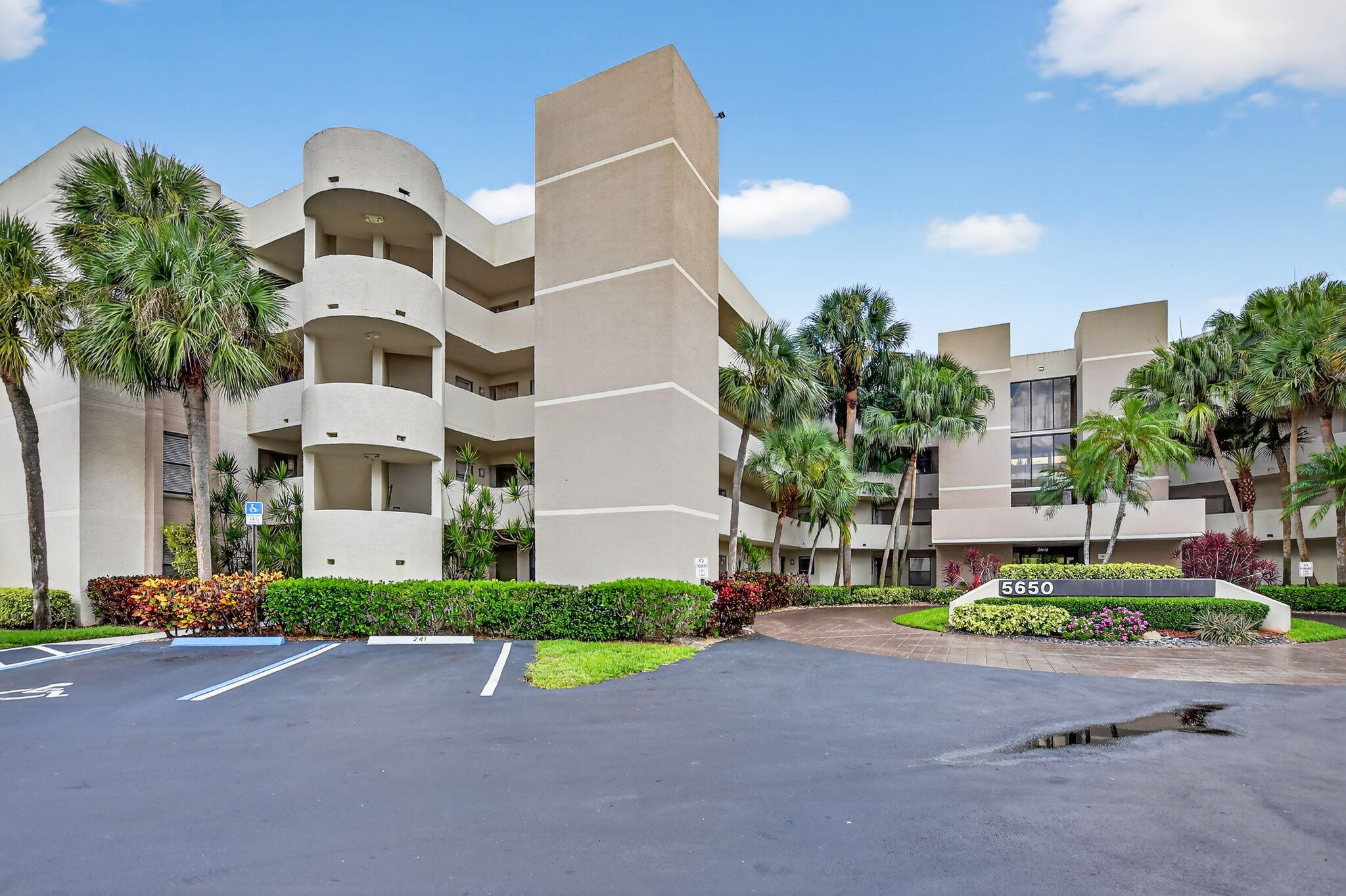 5650 Camino Del Sol, Unit 200 Boca Raton, FL 33433 - Photo 30 of 38 a front view of multi story residential apartment building with yard and sign board