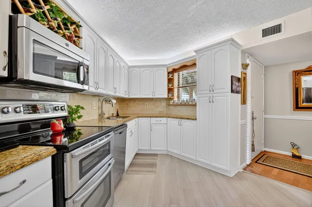 a spacious en suite bathroom with a granite countertop sink mirror and cabinets
