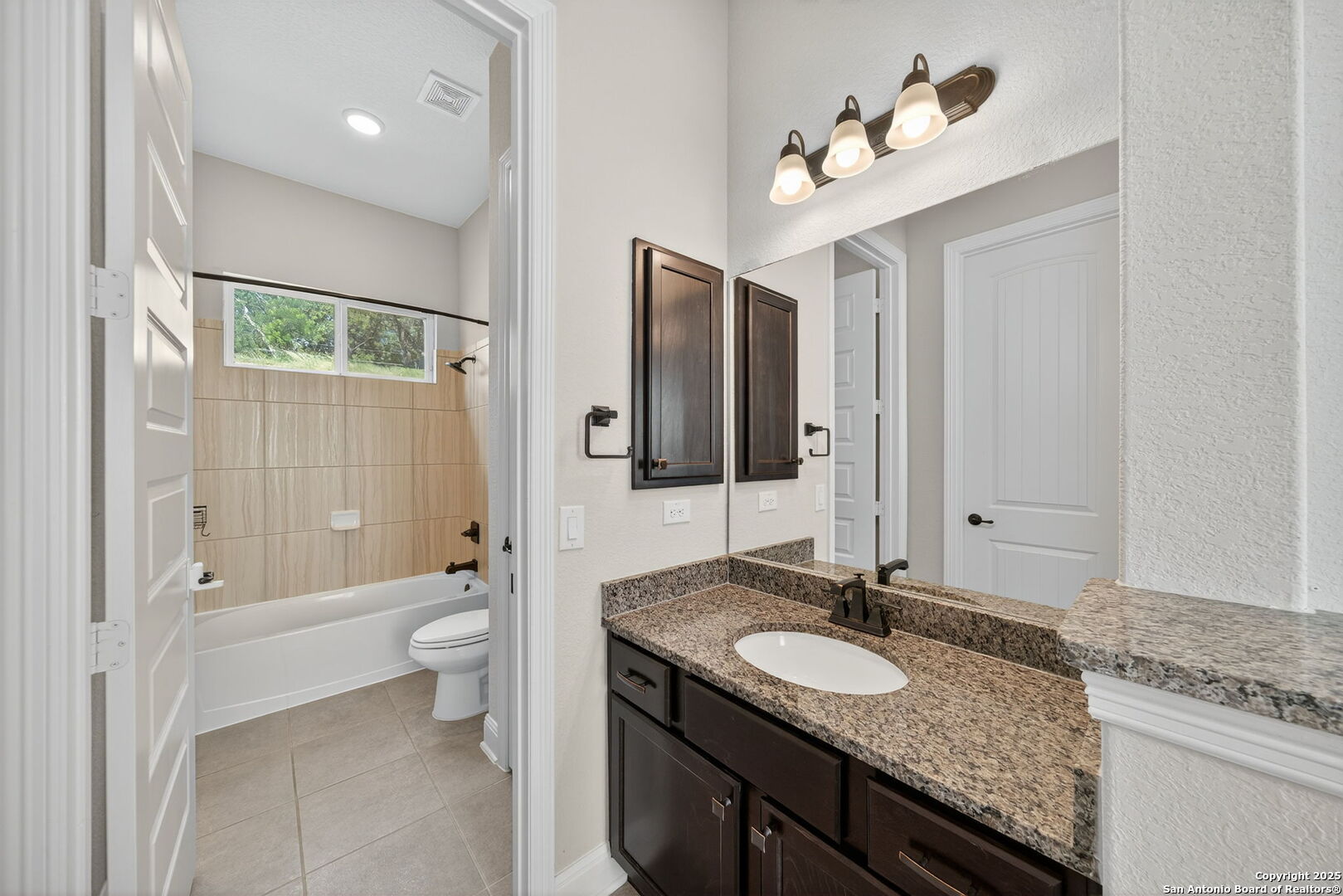 8283 Apache Forest Garden Ridge, TX 78266 - Photo 27 of 42 a bathroom with a granite countertop sink a toilet and a large mirror