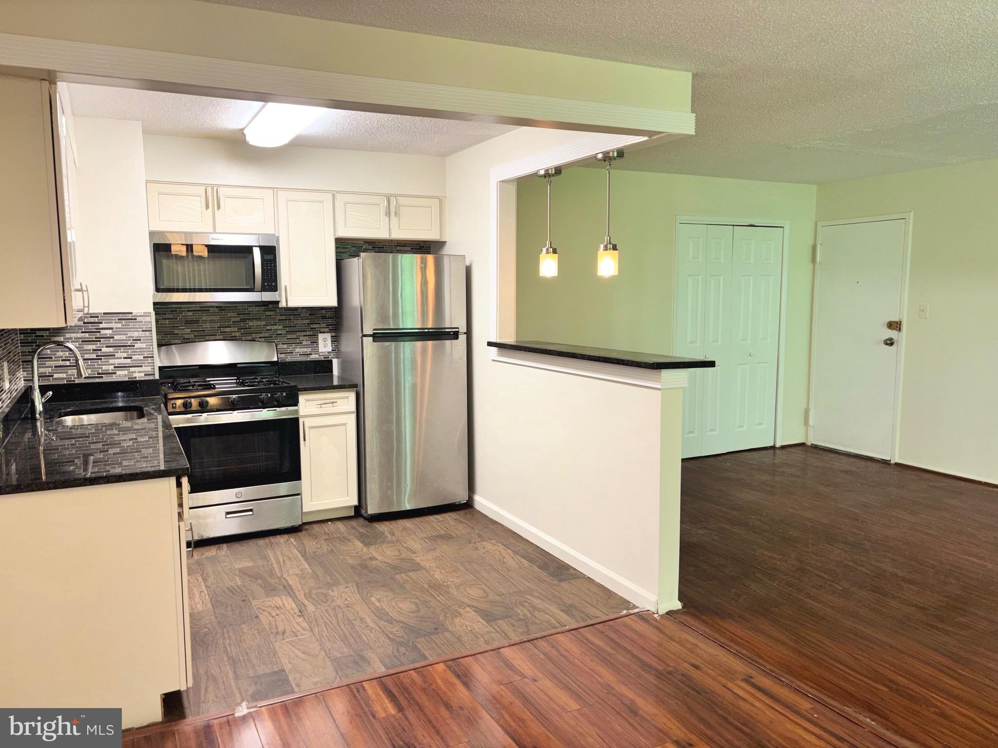 1832 Metzerott Road, Unit 105 Hyattsville, MD 20783 - Photo 11 of 16 a kitchen with granite countertop a refrigerator and a stove top oven