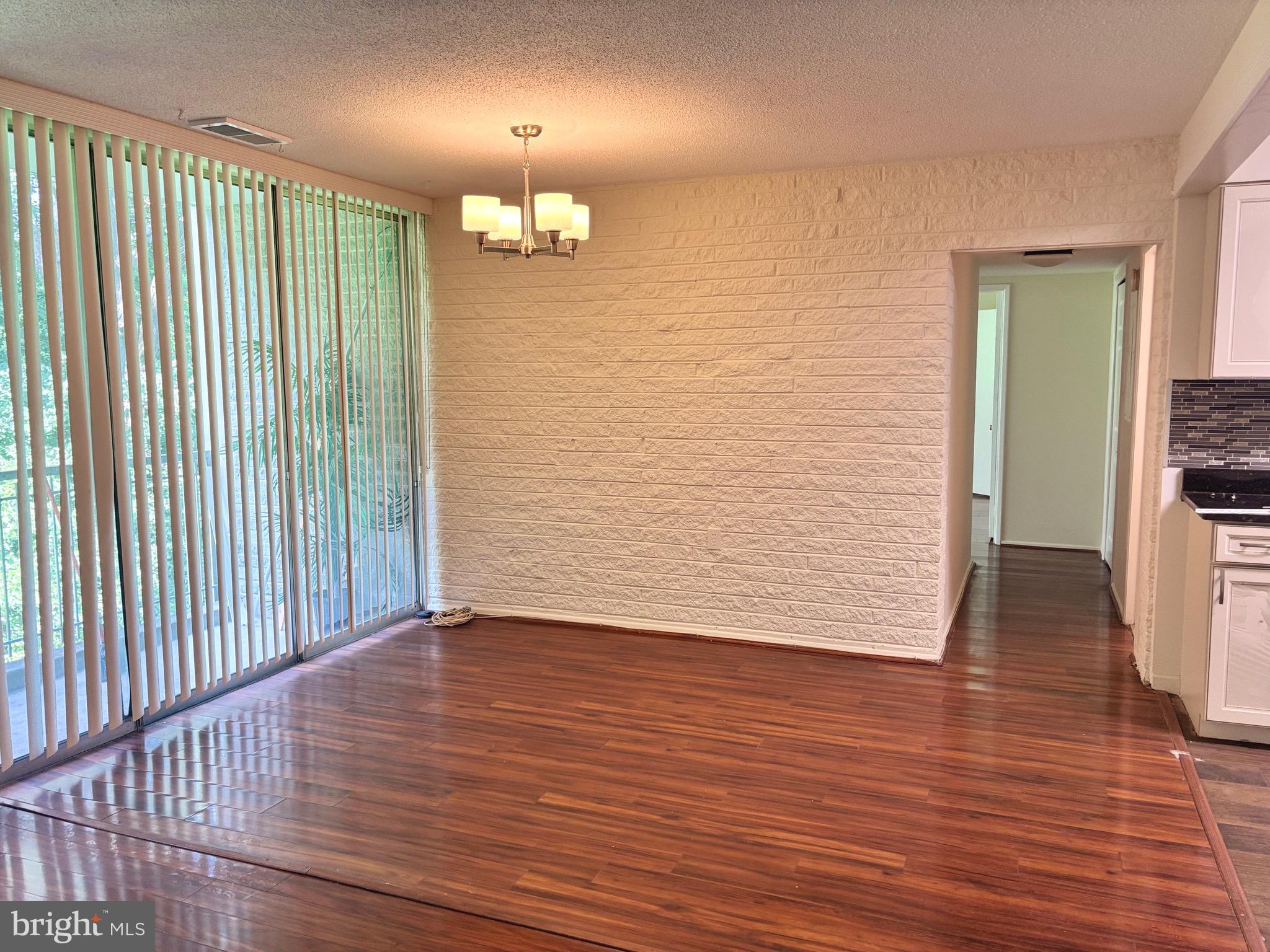 1832 Metzerott Road, Unit 105 Hyattsville, MD 20783 - Photo 2 of 16 an empty room with wooden floor chandelier fan and windows