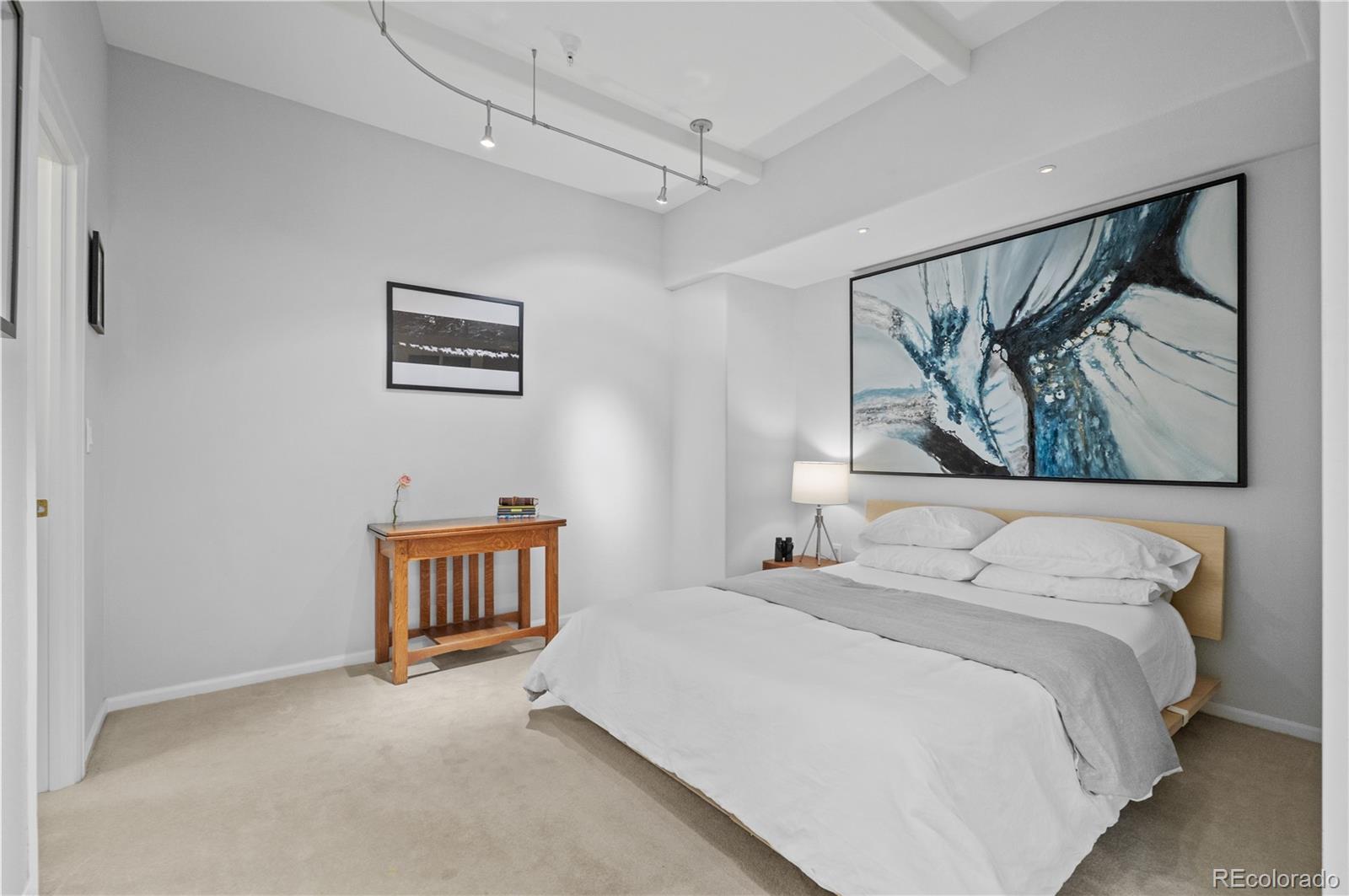 180 Cook Street, Unit 203 Denver, CO 80206 - Photo 28 of 44 a bedroom with a bed and a painting on the wall