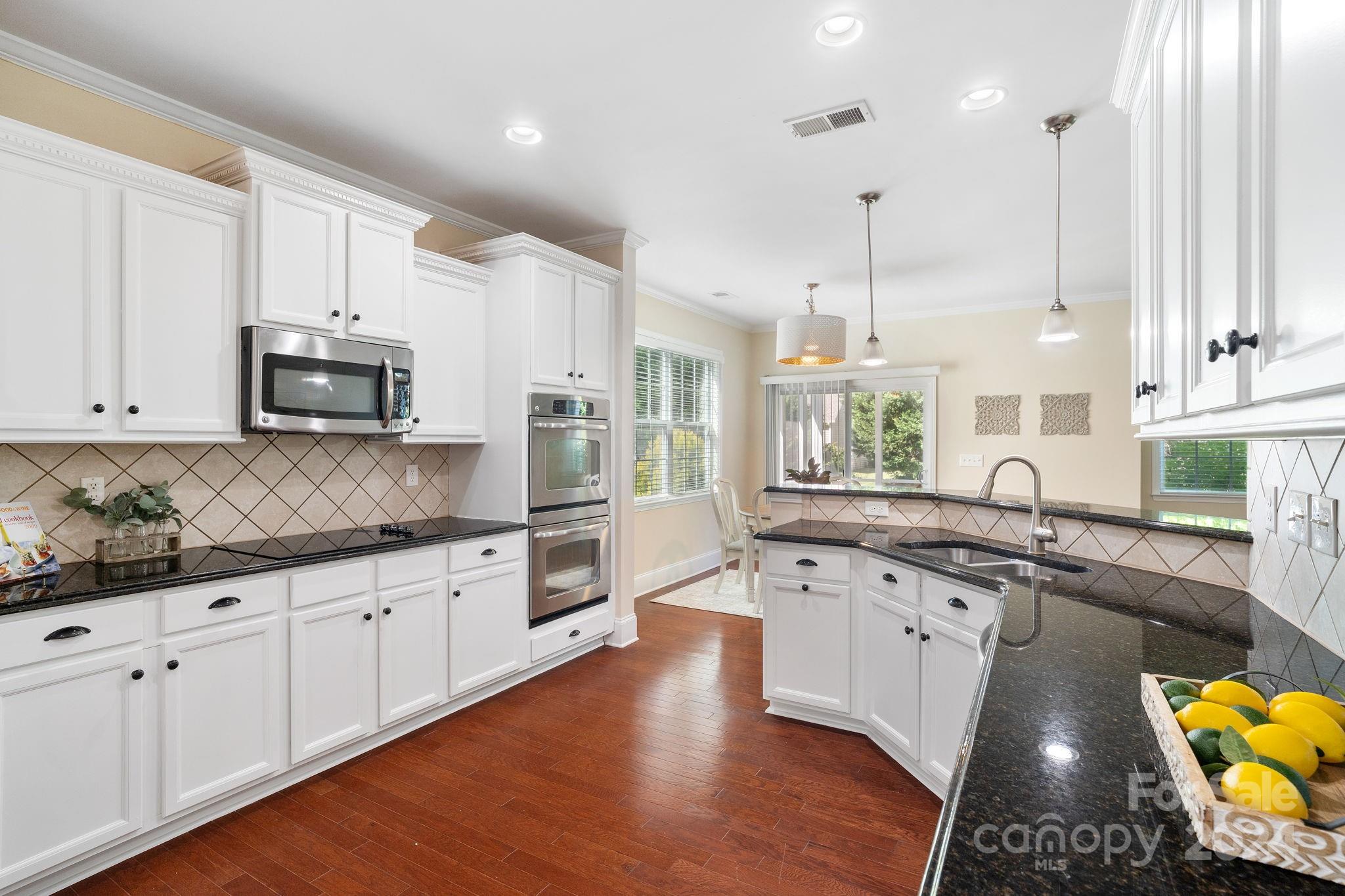 580 Rosemary Lane Fort Mill, SC 29708 - Photo 6 of 37 a large kitchen with stainless steel appliances granite countertop a stove a sink and white cabinets with wooden floor
