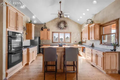 a kitchen with stainless steel appliances granite countertop a stove a sink dishwasher a dining table and chairs with wooden floor