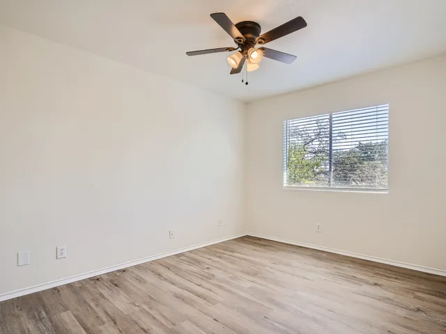 an empty room with a window and a fan