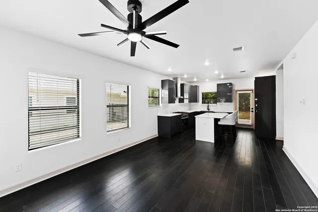 a open kitchen with stainless steel appliances kitchen island a stove a refrigerator a sink dishwasher with a dining table and chairs with wooden floor