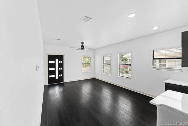 an empty room with wooden floor and windows