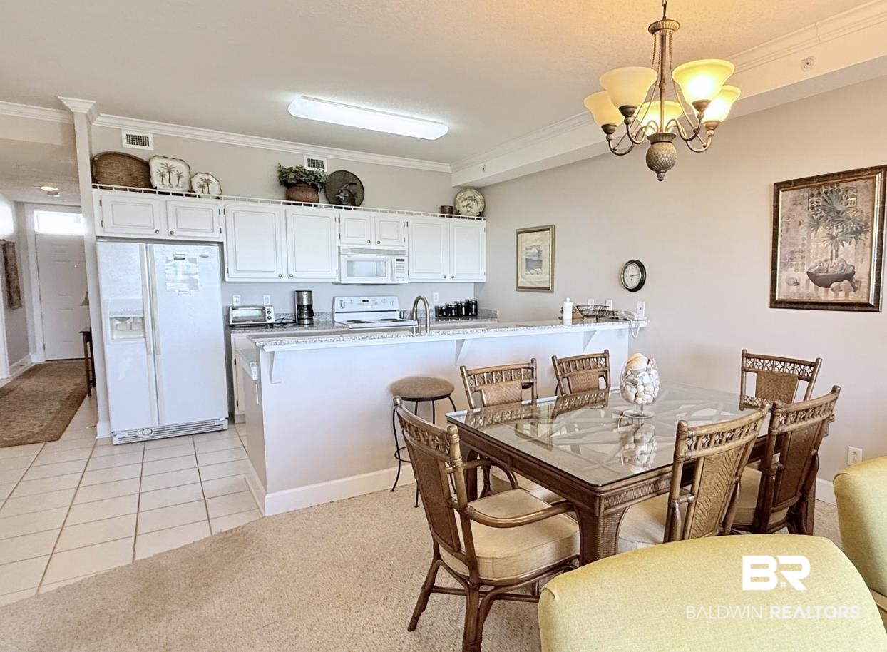 27284 Gulf Road, Unit 212 Orange Beach, AL 36561 - Photo 5 of 35 Dining space featuring ornamental molding, a chandelier, light tile patterned flooring, and light colored carpet