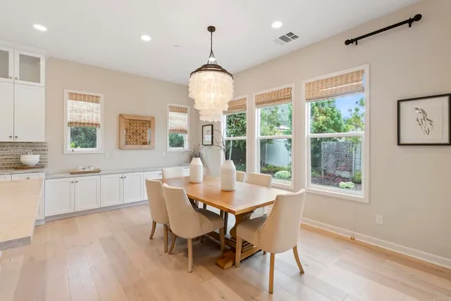 a dining room with wooden floor a chandelier a wooden table and chairs