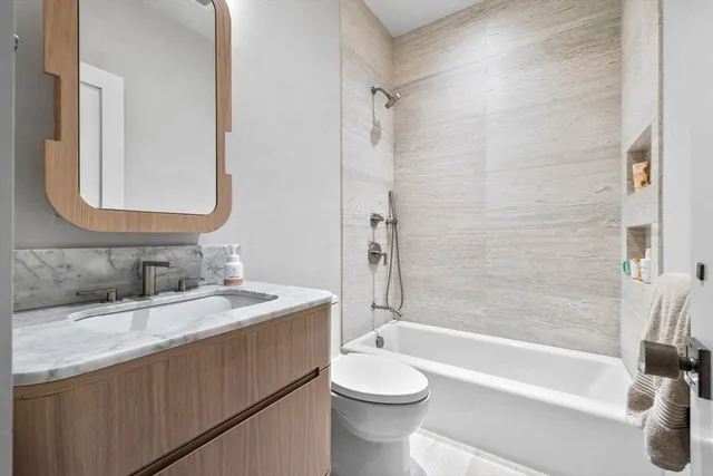 a bathroom with a granite countertop sink toilet mirror and bathtub