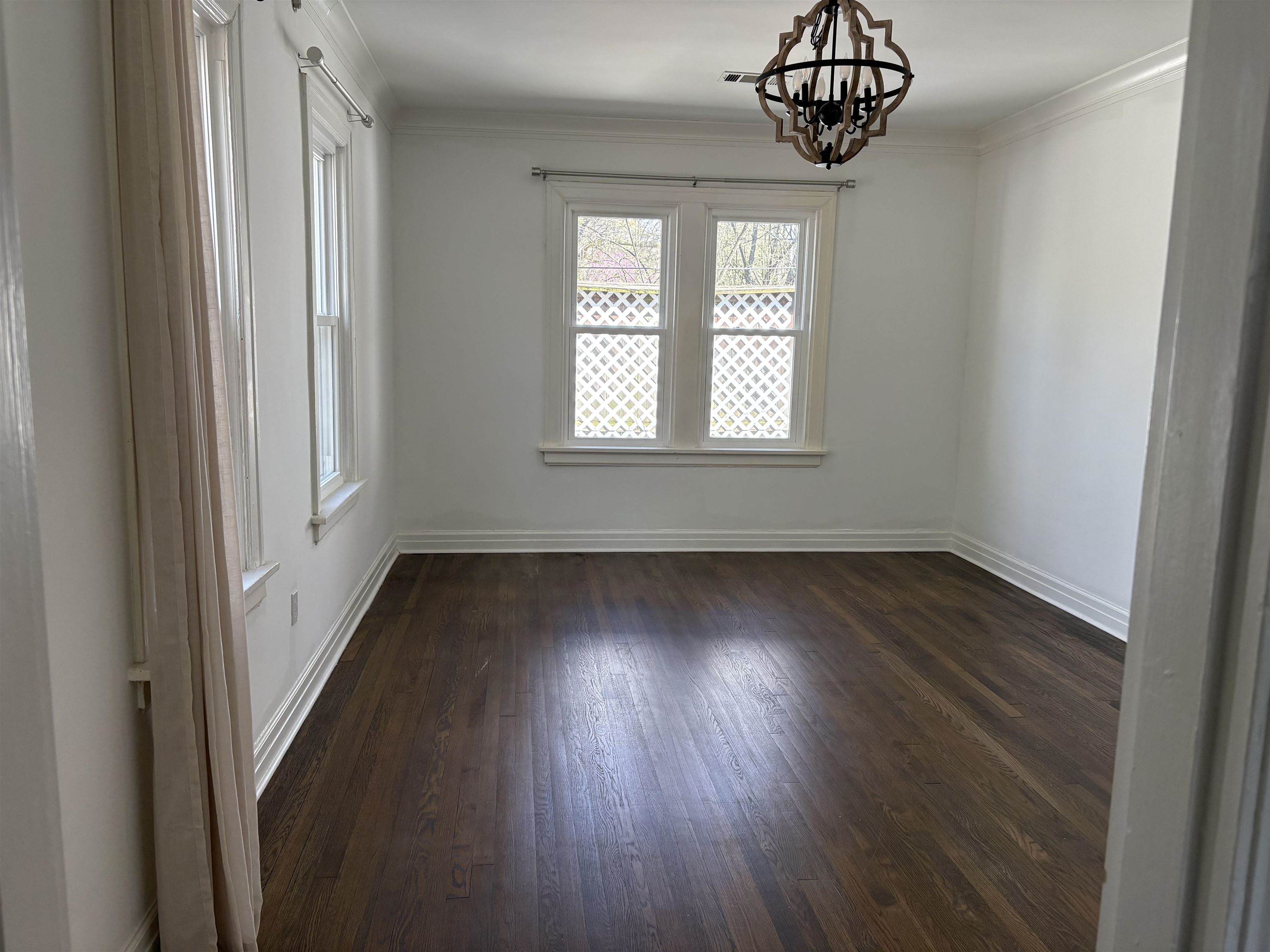 4572 Princeton Road Memphis, TN 38117 - Photo 8 of 24 Empty room featuring dark wood-style flooring, suspended lighting, and crown molding